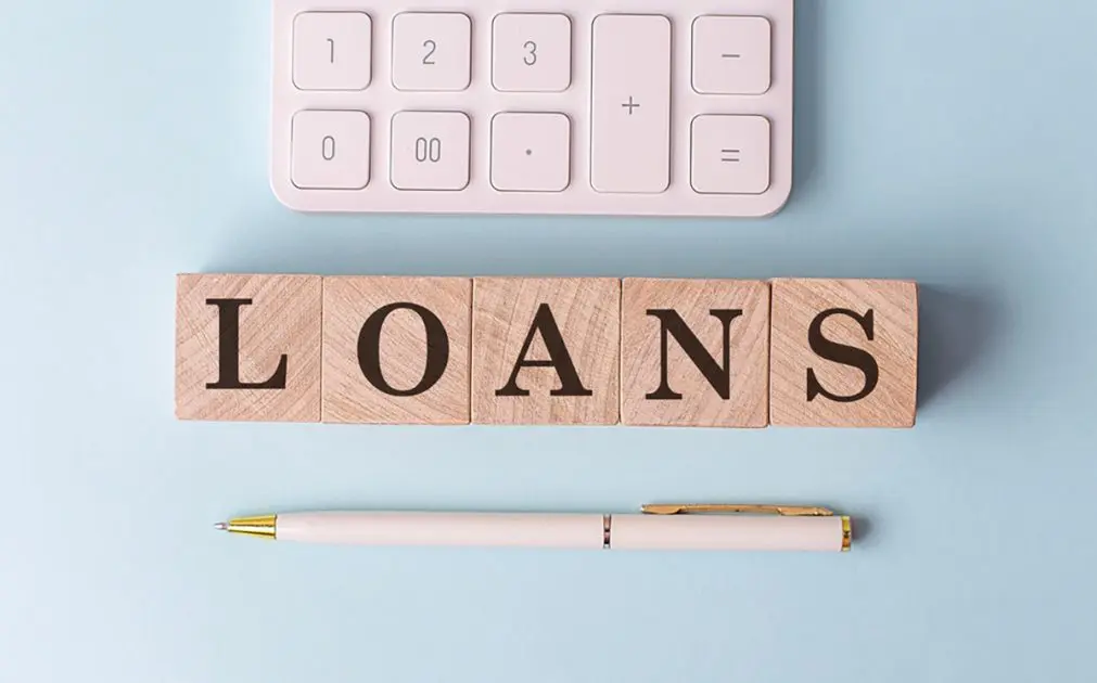 LOANS on a wooden cubes with pen and calculator, financial concept
